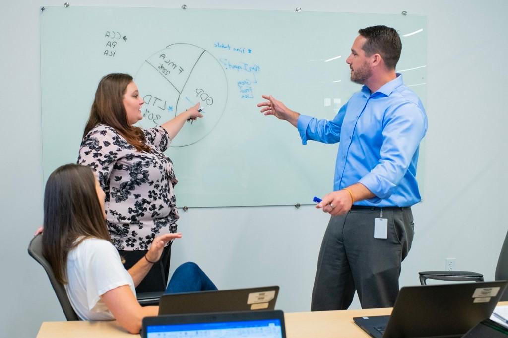 students work on a pie chart displaying statistics on a dry erase board