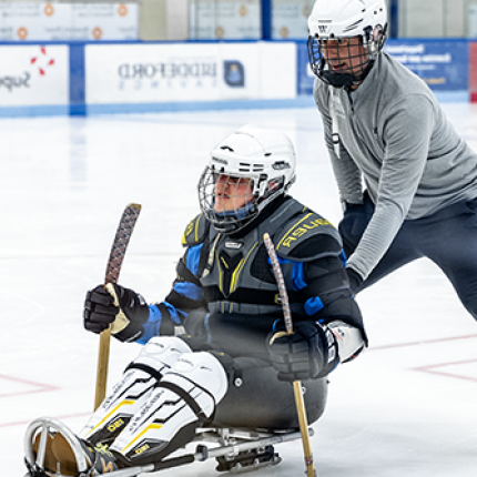 A UNE student pushes a man on a hockey sled as part of a demonstration