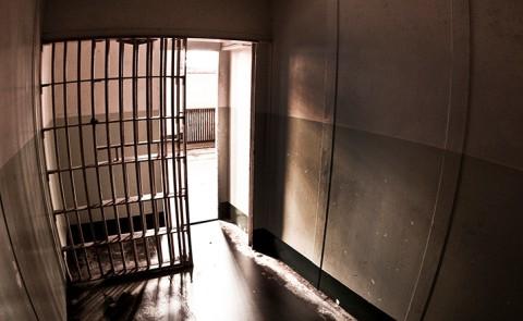 A dark photo shows the silhouette of a jail cell